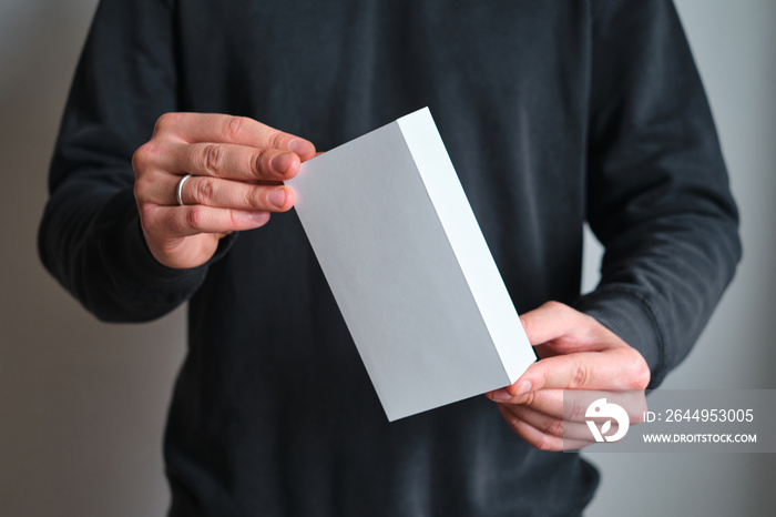 Man holding in hand small paper box. Blank packing, empty space. Male with a new package. Postal service, delivery. White paper. Gift box, present. Box close up. People communication. Carton case