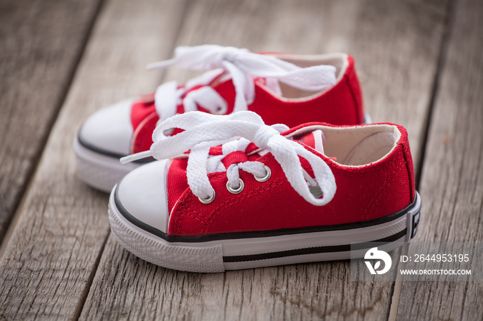 Red baby sneakers on wooden background. Vintage