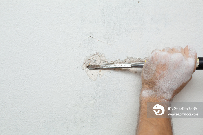 Repair of the premises. A man makes a ditch for laying cable into the wall. Laying electrical wiring in the wall.