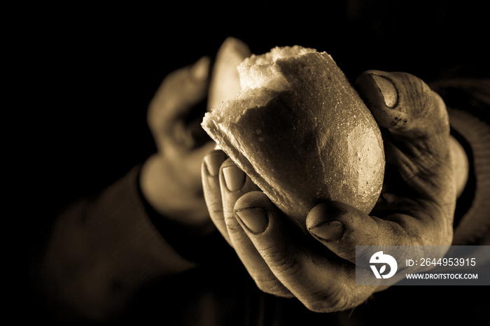 Helping hand giving a piece of bread. Poor Man sharing Bread, Helping Hand Concept. Amber close up