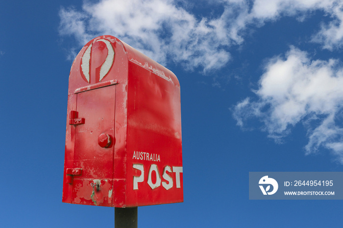 red and white Australia Post post box in a blue cloudy sky