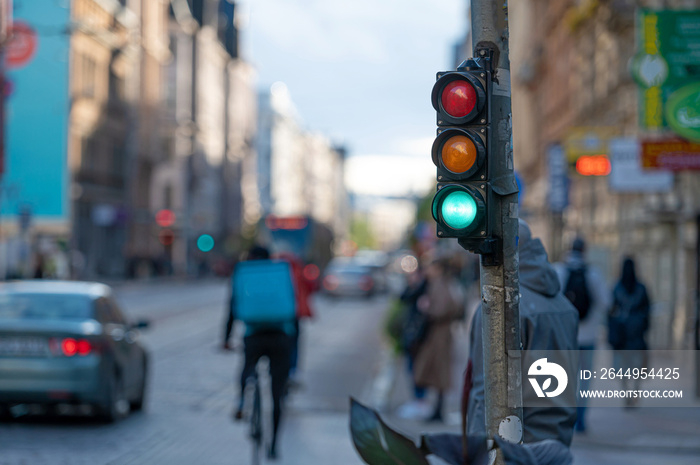 view of city traffic with traffic lights, in the foreground a semaphore with a green light, closeup