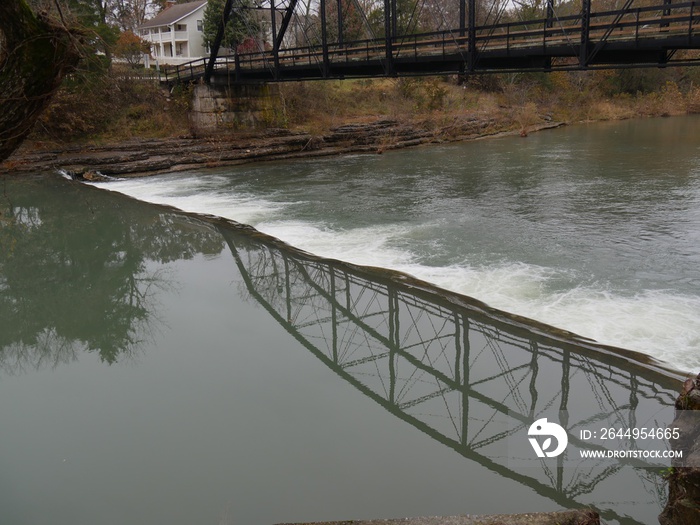 Scenic shot of a bridge refelcted in the waters of War Eagle river in Rogers, Arkansas.