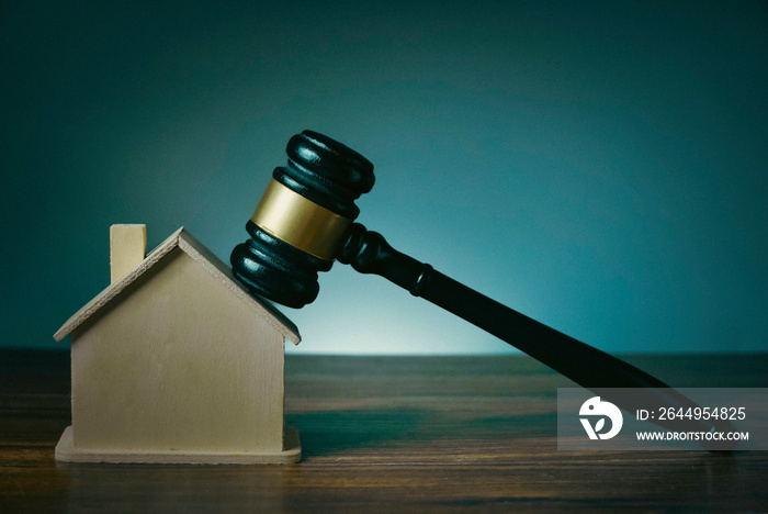 Wooden judge gavel over a house model. Mortgage, auction, bankruptcy or divorce concept.