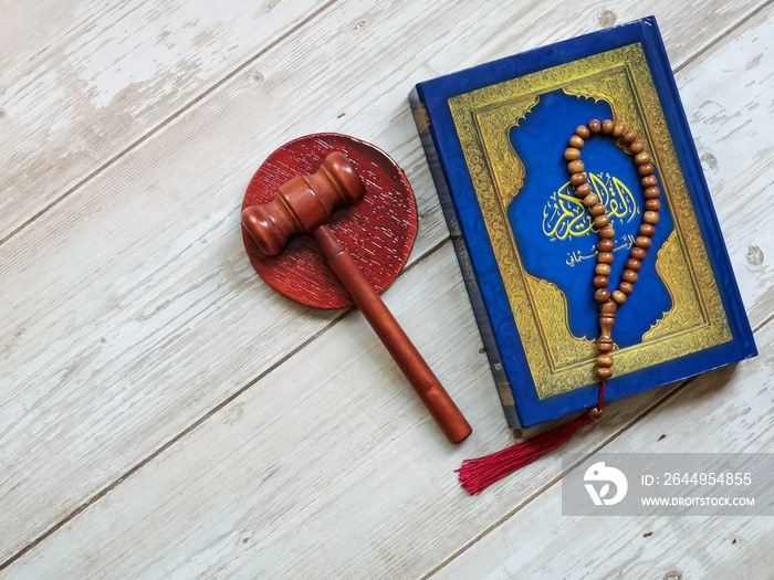 Selective focus Holy Quran written arabic calligraphy meaning of Al Quran with gavel isolated on white background. Islamic law concept.