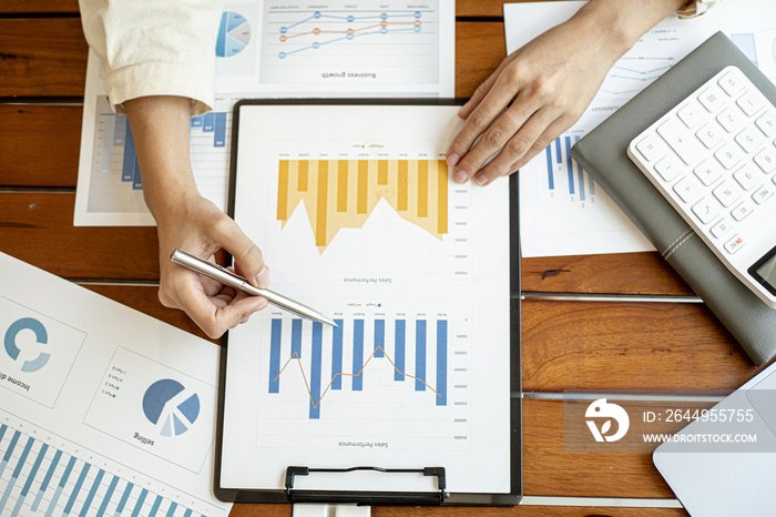 Top view The desk of a financial businesswoman examining company financial documents, she examines the company’s financial documents in the datasheet in the form of a bar chart showing income.