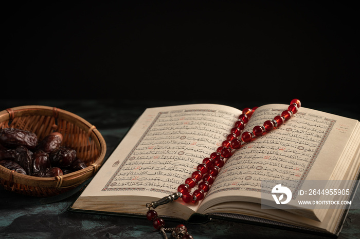 Islamic concept: The holy Quran and Tasbih (rosary beads) on dark background