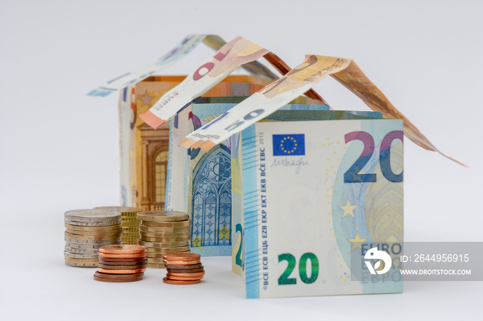 Trois maisons faites en billets de 10, 20, et 50 euros, avec quelques pièces de monnaie