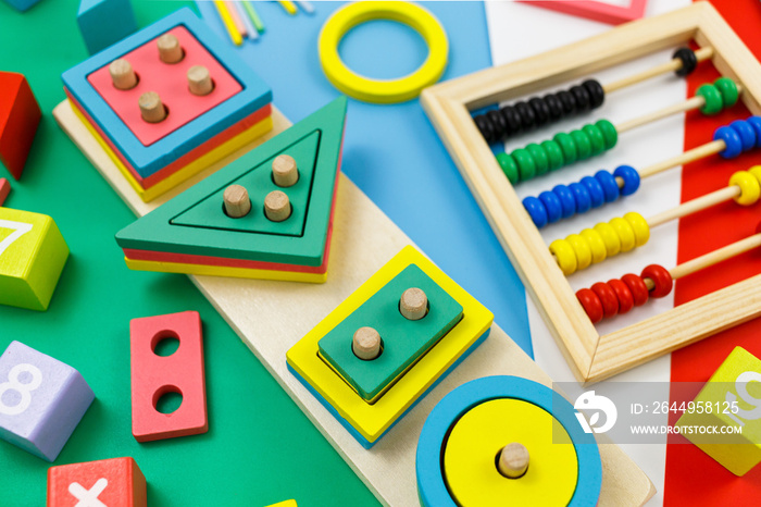 Multicolored wooden blocks on red background. Trendy puzzle toys. Geometric shapes: square, circle, triangle, rectangle. Educational toys for kindergarten, preschool or daycare. Back to school