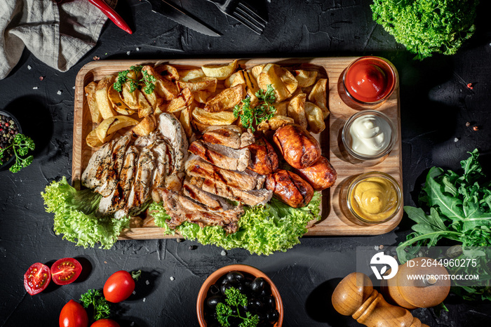 Grilled meat with sauces, set meat beef pork and chicken with vegetables on dark background. Mix of different snacks and appetizers