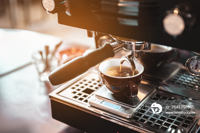 Close-up coffee maker that is professionally extracting coffee by barista with a deep white glass in the evening sun light. coffee, extraction, deep, machine, make, barista concept.