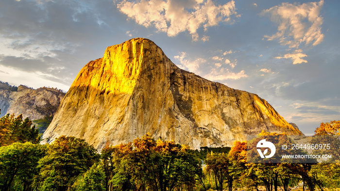 Setting Sun casting glowing sunlight over the famous El Capitan granite rock in Yosemite National Park, California, USA