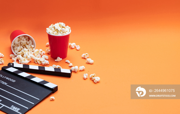 Clapperboard and pop corn on orange color background