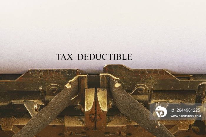 Closeup on vintage typewriter. Front focus on letters making TAX DEDUCTIBLE  text. Business concept image with retro office tool