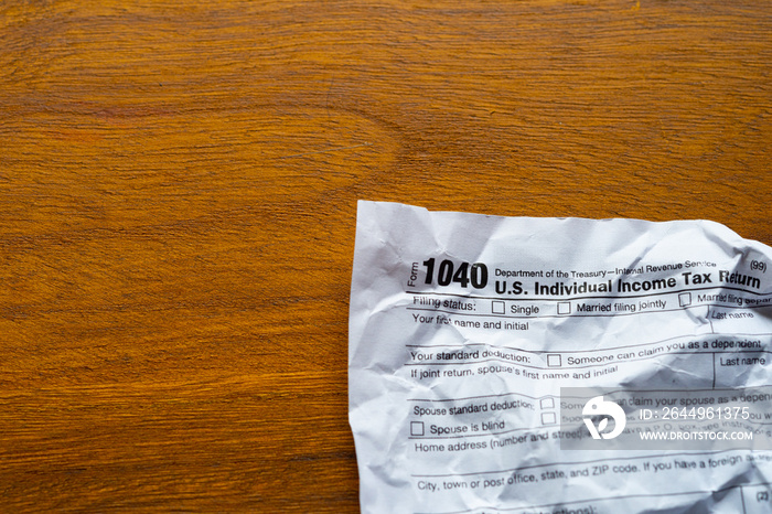 Paper tax form, crumpled up on a wooden table