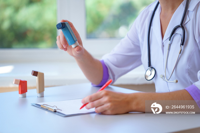 Doctor writes prescription for asthma inhaler to asthmatic patient during medical consultation and examination. Healthcare