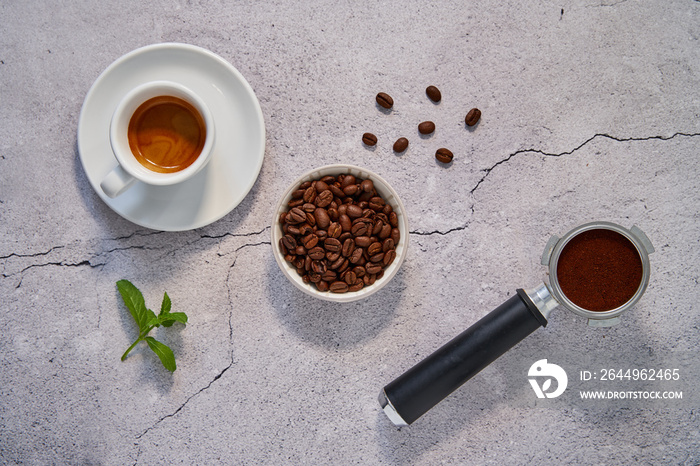 Top down Foto von einer Espresso Tasse, einem Siebträger, Kaffeebohnen und einem Pfefferminzblatt. Köstlicher italienischer Kaffee.