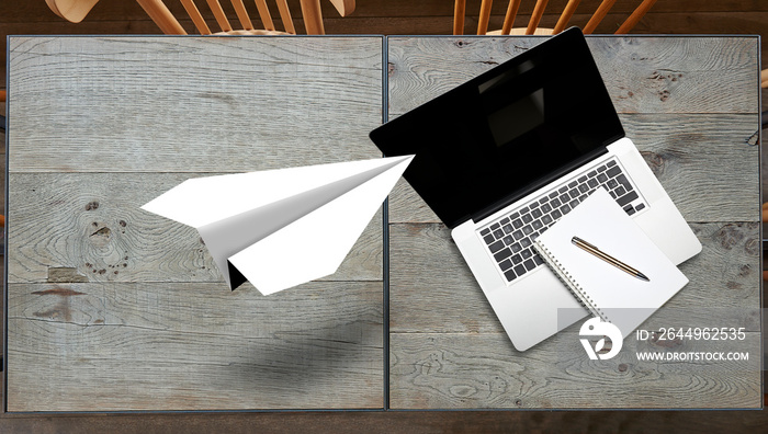 Paper plane origami flying over textured wooden table