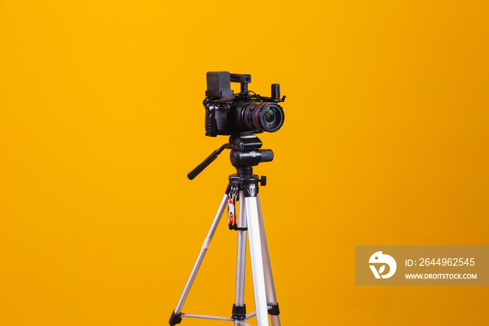 tripod cinematographic camera on yellow background