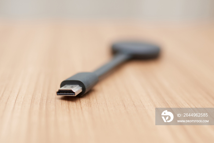 Chromecast on a wooden background, is focused on the HDMI connection