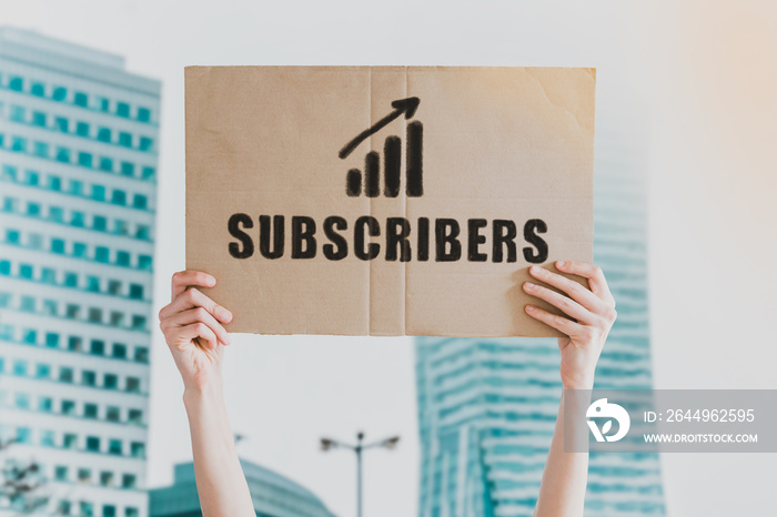 The word   Subscribers   and going up c drawn on a carton banner in men’s hand. Human holds a cardboard with an inscription: Subscribers