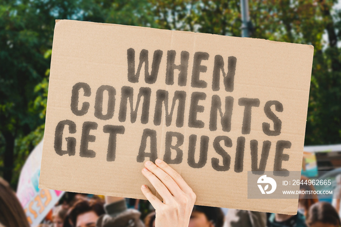 The phrase   When comments get abusive   on a banner in men’s hand with blurred background. Communication. Relationship. Dangerous. Behaviour. Friendship. Emotional. Negotiation. Psychology. Society