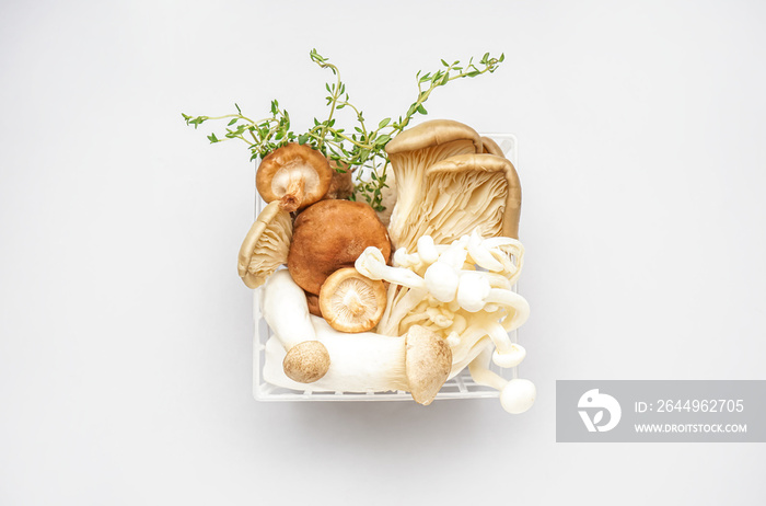 Basket with fresh mushrooms and thyme on light background