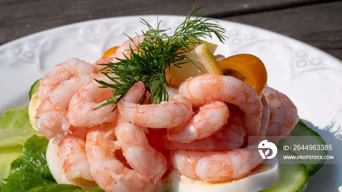 Close up of peeled fresh shrimps on white bread, making a delicious Swedish shrimp sandwich (räkmacka). Seafood and food preparation concept.