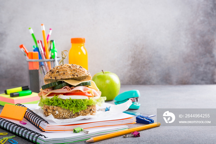 Healthy lunch for school with sandwich, fresh apple and orange juice. Assorted colorful school supplies. Copy space.