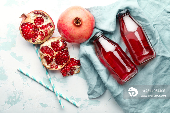 Composition with bottles of fresh pomegranate juice on light background