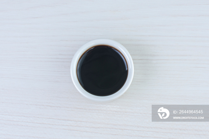 teriyaki sauce, in white ceramic bowl on white wooden background