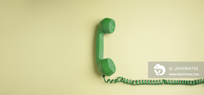 Green Vintage Retro Telephone Handset Hanfing on Pink background. Old Object from 1980-1990, Technology and Communication in the Past. Clean, Colourful  and Minimal