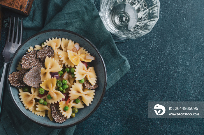 Pasta with black truflle and green peas in blue bowl.