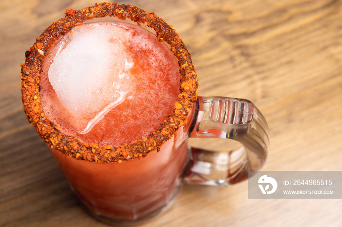 Michelada beer with tomato juice. Clamato with beer on wooden table. Mexican drink concept.