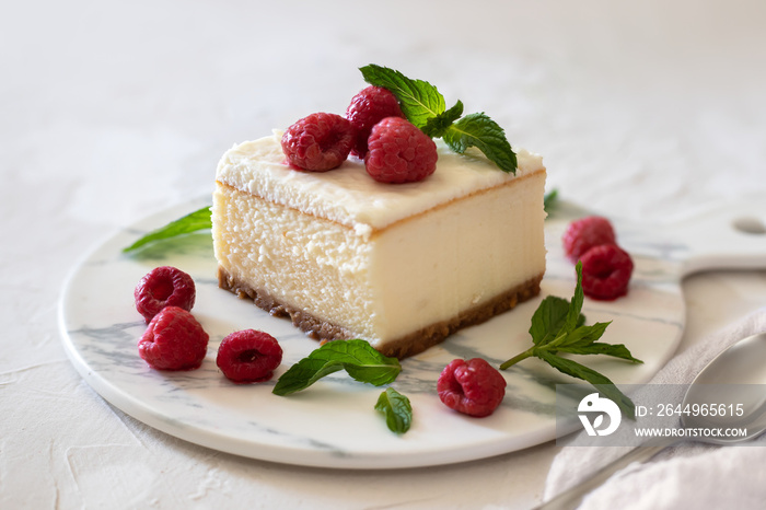 Cheesecake with raspberries garnished with mint. On a light background