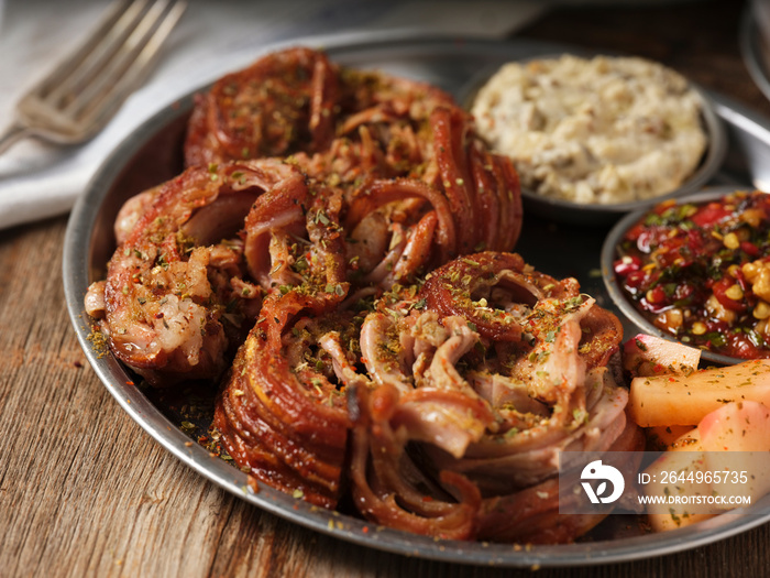 kokorec with mezes with a fork on a metal plate on wooden background