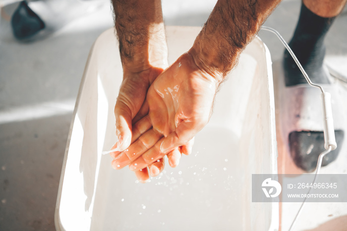 man washes his hands in a bucket