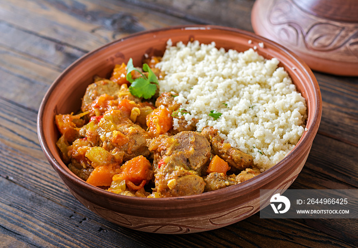 Traditional tajine dishes, couscous  and fresh salad  on rustic wooden table. Tagine lamb meat and pumpkin.