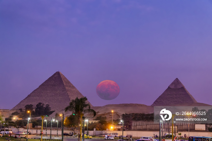 View of the great pyramids of Giza at sunset from Giza city with big full moon rising