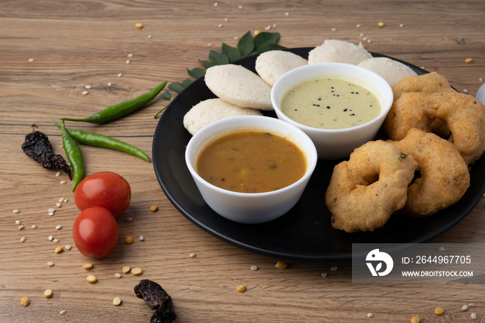 South Indian breakfast-Idli, sambar, wada, coconut chutney. Served in plate wooden background