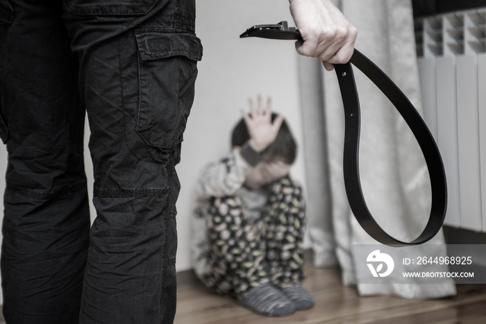 Aggressive parent with belt and frightened child in corner. Domestic violence. Abused child, aggression in the family