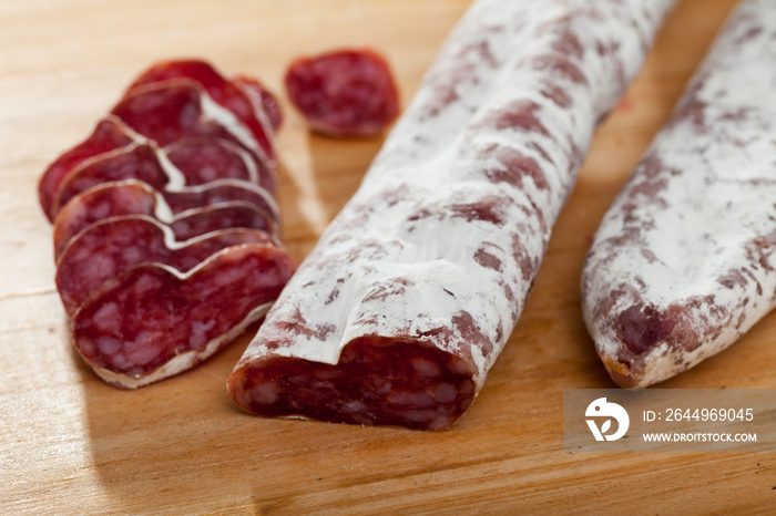 Traditional Catalan thin dry cured pork sausage Fuet sliced on wooden surface