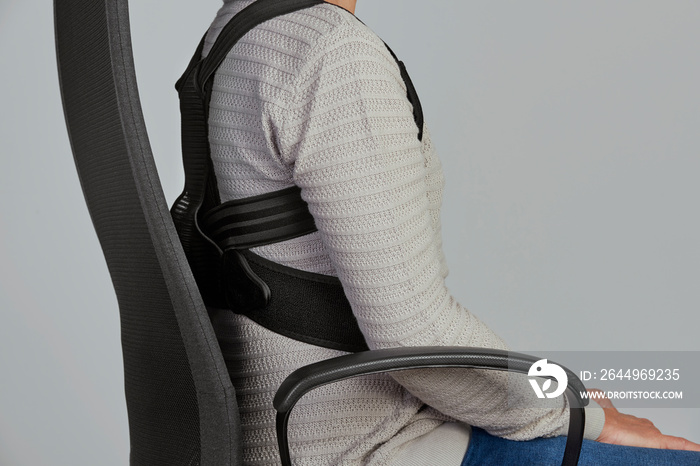 man wearing a posture corrector while sitting