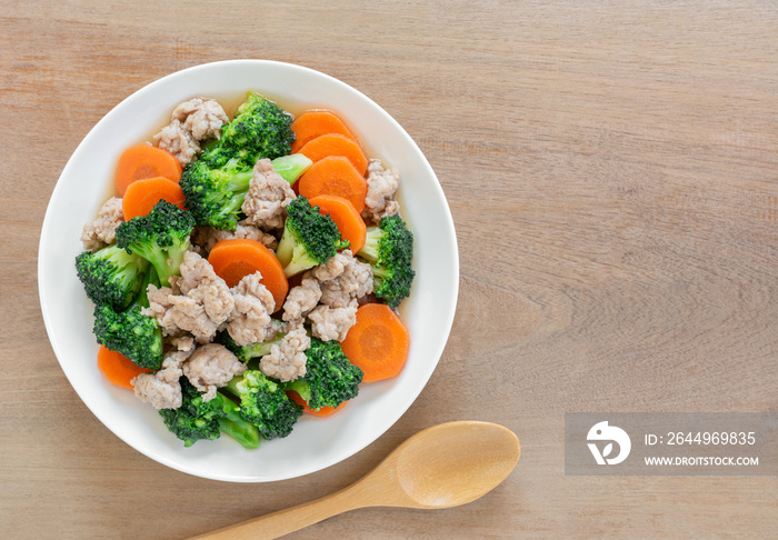 top view of stir fried broccoli with pork in a ceramic dish on wooden table. homemade style food concept.