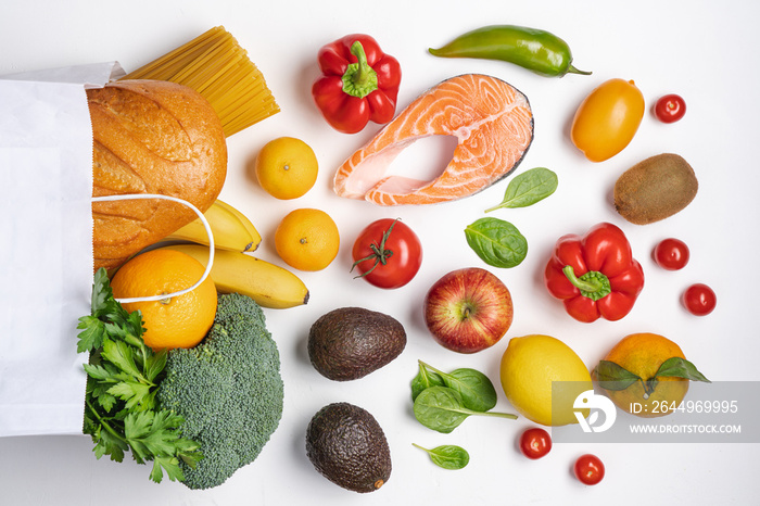 Healthy food  background. Vegetables, fruits, bread, pasta and salmon in paper bag. Variety balanced of healthy food products on white background