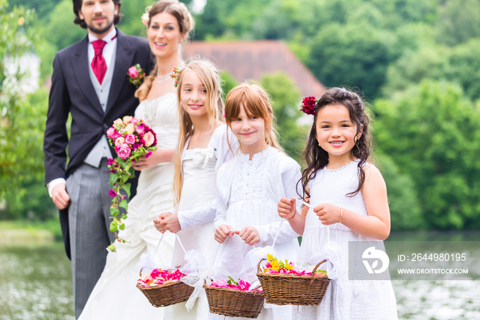 Wedding couple bride and groom with flower children or bridesmaid in white dress and flower baskets