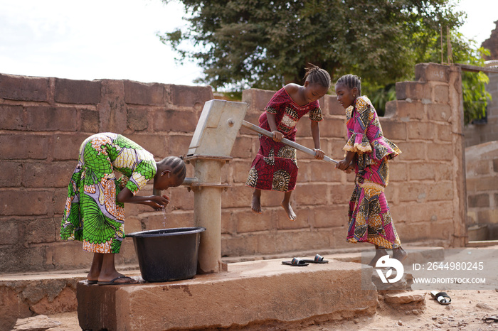 African Girls Having Trouble In Pumping Water Out Of An Almost Dry Public Well