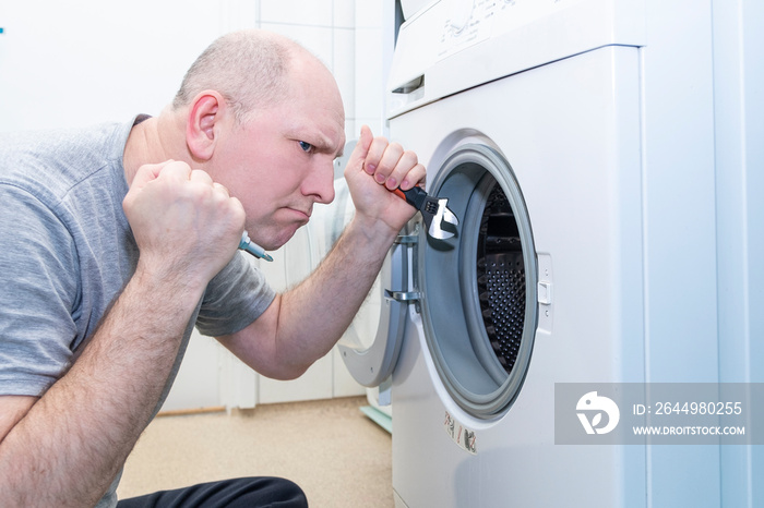 Caucasian man repairing a washing machine, repair and maintenance.