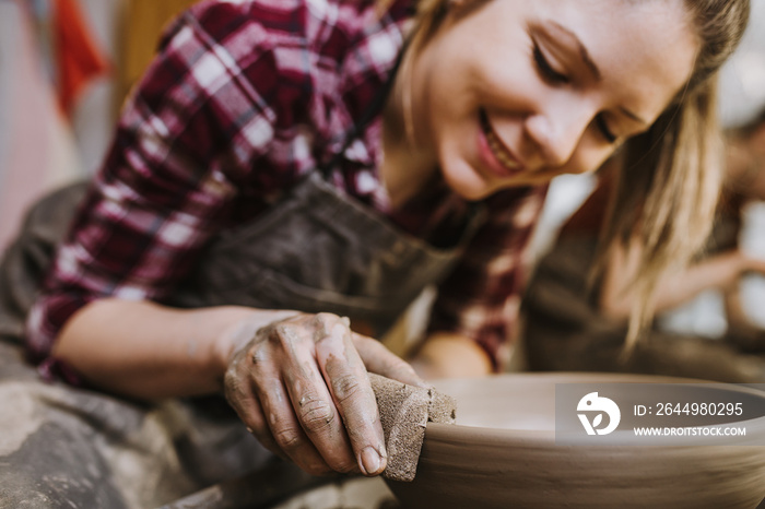 Female potter making clay pottery on a spin wheel.