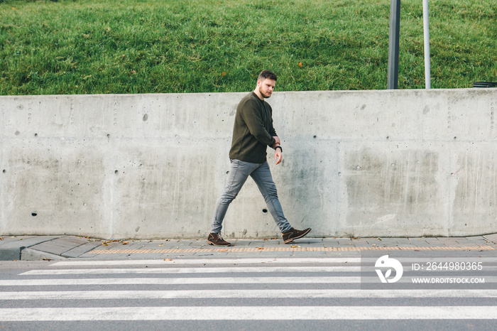 man in sweater walking by sidewalk